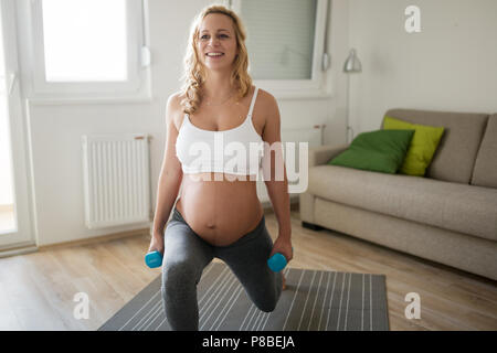 Sportliche schwangere Frau Übungen zu Hause Stockfoto