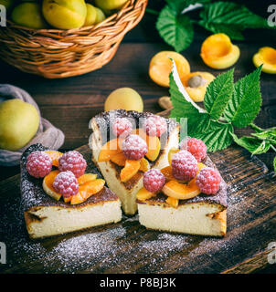 Stücke von Quark Torte mit Erdbeeren und Aprikosen auf einem braunen Holz- Board, in der Nähe Stockfoto