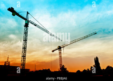 Turmdrehkrane in Silhouette auf einer Baustelle Stockfoto