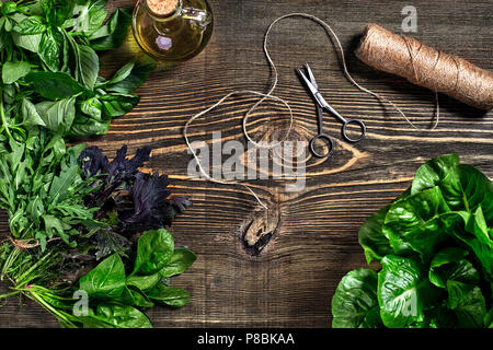 Auswahl an frischen Kräutern auf Holz- Hintergrund. Frisch geerntete Kräuter wie Basilikum, Rucola. Ansicht von oben. Kopieren Sie Platz. Stockfoto