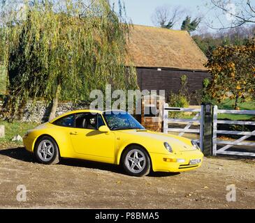 Porsche 911 Targa coupe 3.6L Motor 1996 Modell Jahr in gelber Farbe außerhalb eines Country Cottage Stockfoto