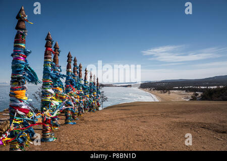 Holzsäulen mit bunten Bändern auf Seeküste im Winter das Meer Stockfoto