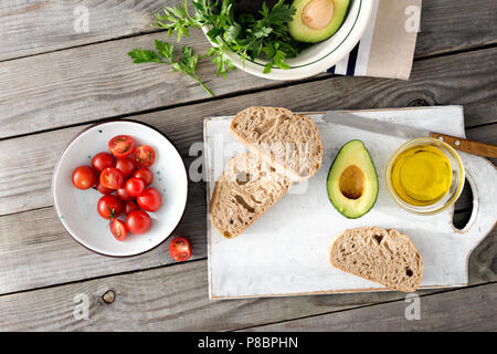 Ansicht von oben Zutaten zum Kochen Italienisch Bruschetta mit Tomaten und Avocado auf hölzernen Tisch Stockfoto