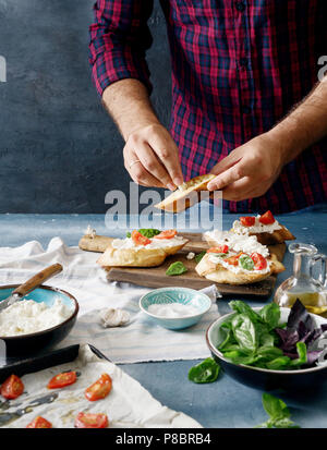 Mann kochen Italienisch Bruschetta mit Tomaten, Basilikum und Käse Stockfoto