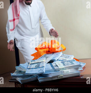 Saudi-arabischer Mann überrascht mit Stapeln von Geld auf der Seite Tabelle zu Hause Stockfoto