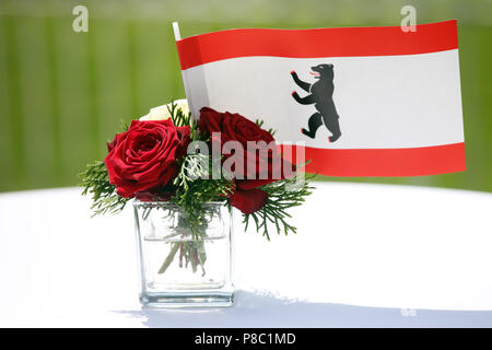 Hoppegarten, Deutschland, Flagge des Landes Berlin und rote Rosen in einer kleinen Vase Stockfoto