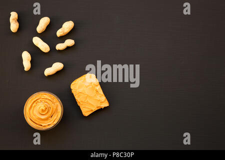 Schüssel mit Erdnussbutter, ohne schale Erdnüsse auf schwarzem Hintergrund, Ansicht von oben. Kopieren Sie Platz. Stockfoto