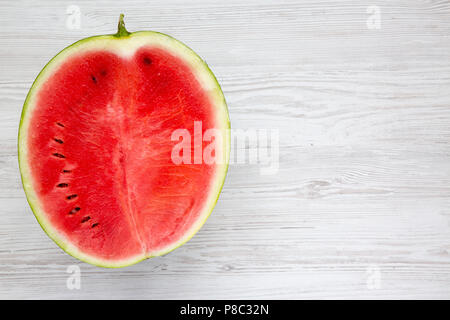 Ansicht von oben, halb geschnittenen Wassermelone auf weissem Holztisch. Von oben. Kopieren Sie Platz. Stockfoto