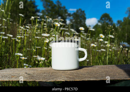 Weiß Lagerfeuer Emaille Tasse mockup mit blühenden daisy-Feld. Leere Becher mock up für Design Promotion. Stockfoto