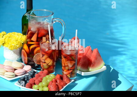 Pool Party mit Sangria Krug, Obst, Cocktails und Erfrischungen am Pool. Sommer Lifestyle, topaktueller Urlaub, Spaß und Entspannung. Stockfoto