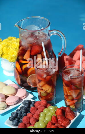 Pool Party mit Sangria Krug, Obst, Cocktails und Erfrischungen am Pool. Sommer Lifestyle, topaktueller Urlaub, Spaß und Entspannung. Stockfoto