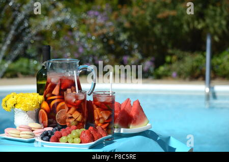 Pool Party mit Sangria Krug, Obst, Cocktails und Erfrischungen am Pool. Sommer Lifestyle, topaktueller Urlaub, Spaß und Entspannung. Stockfoto