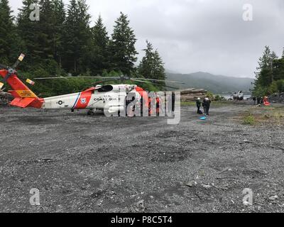 Ein Coast Guard Air Station Sitka MH-60 Jayhawk Helikopter das fliegende Personal und das Bodenpersonal in Ketchikan Freiwillige Rescue Squad Personal tendenziell zu den Überlebenden von einem abgestürzten Flugzeug auf dem Mount Jumbo auf Prince of Wales Island, Alaska, 10. Juni 2018. Alle 11 Personen an Bord überlebten und wurden von einem Jayhawk Helikopter aircrew gehisst und medizinische Personal für die Triage genommen, bevor es weiter nach Ketchikan für übergeordnete medizinische Versorgung berücksichtigt. U.S. Coast Guard Foto. Stockfoto