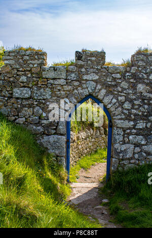 Ein torbogen durch eine Mauer aus Stein, die zu einem Garten auf Lundy Island. Es ist der Eingang zum Garten von einem Ferienhaus genannt. Stockfoto