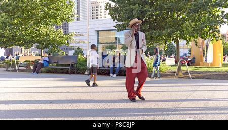 Ein älterer Rapper spricht Black man per Handy an, während er durch das Einkaufszentrum im Freien in der Innenstadt von Cleveland, Ohio, USA läuft. Stockfoto