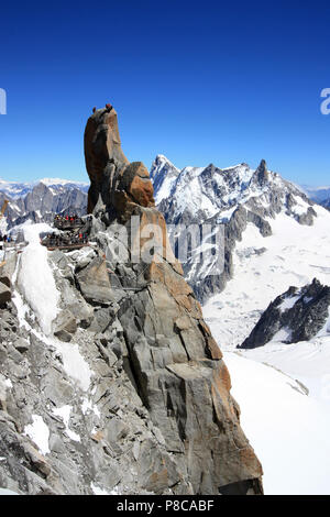 Kletterer auf der Spitze eines Pinnacle während Touristen beobachten Von den aussichtsplattformen an der Aiguille-du-Midi in Frankreich Stockfoto