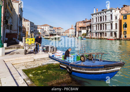 Zwei Männer laden Wasserflaschen und Dosen zu blauen Boot über den Kanal an einem sonnigen Tag, Venedig Italien Stockfoto
