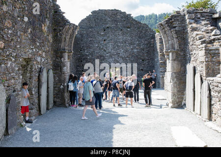 Glendalough, Wicklow, Irland. 10. Juli 2018: Touristen, die in der Glendalough Tal mit seinen berühmten Kloster an einem sonnigen Dienstag Nachmittag. Stockfoto