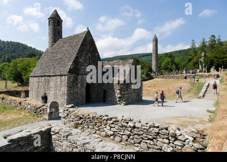 Glendalough, Wicklow, Irland. 10. Juli 2018: Touristen, die in der Glendalough Tal mit seinen berühmten Kloster an einem sonnigen Dienstag Nachmittag. Stockfoto