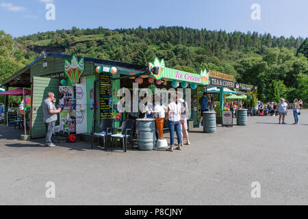 Glendalough, Wicklow, Irland. 10. Juli 2018: Touristen, die in der Glendalough Tal mit seinen berühmten Kloster an einem sonnigen Dienstag Nachmittag und Stoppen für die Eis und Snacks am Lough Kabine Takeaway. Stockfoto