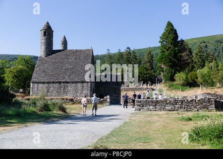 Glendalough, Wicklow, Irland. 10. Juli 2018: Touristen, die in der Glendalough Tal mit seinen berühmten Kloster an einem sonnigen Dienstag Nachmittag. Stockfoto