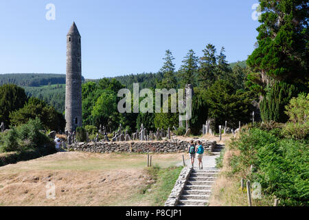 Glendalough, Wicklow, Irland. 10. Juli 2018: Touristen, die in der Glendalough Tal mit seinen berühmten Kloster an einem sonnigen Dienstag Nachmittag. Stockfoto