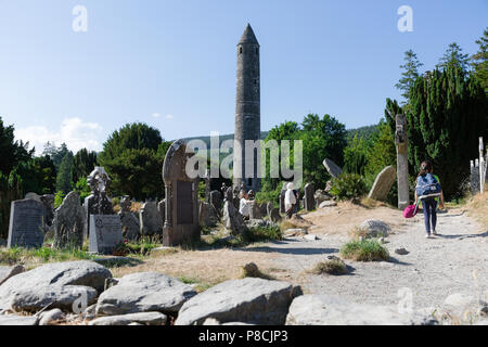 Glendalough, Wicklow, Irland. 10. Juli 2018: Touristen, die in der Glendalough Tal mit seinen berühmten Kloster an einem sonnigen Dienstag Nachmittag. Stockfoto