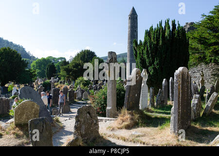 Glendalough, Wicklow, Irland. 10. Juli 2018: Touristen, die in der Glendalough Tal mit seinen berühmten Kloster an einem sonnigen Dienstag Nachmittag. Stockfoto