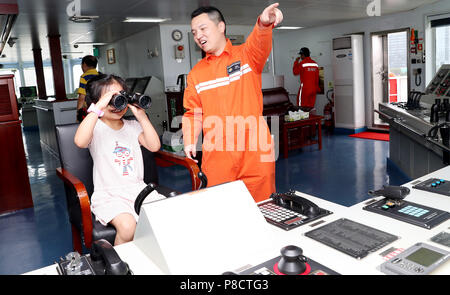 Shanghai. 11. Juli 2018. Ein Besatzungsmitglied (R) interagiert mit einem jungen Besucher auf der Dong Hai Jiu 101 Rettung Schiff während ein Schiff Tag der offenen Aktivität die 2018 Tag der Meere von China Kennzeichnung im Osten Chinas Shanghai, 11. Juli 2018. Die 2018 Tag der Meere von China wurde am Mittwoch beobachtet. Credit: Fang Zhe/Xinhua/Alamy leben Nachrichten Stockfoto