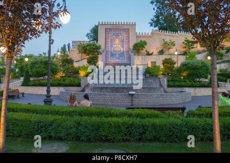 Kaskadenbrunnen mit dekorativen grünen Pflanzen an den Seiten gegen eine Wand Hintergrund mit einem grossen Ornament in der Mitte. Für ihr Design Stockfoto