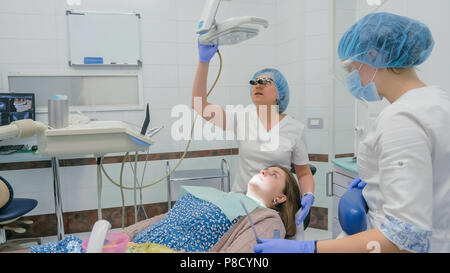 Frau beim Zahnarzt Klinik erhält der zahnmedizinischen Behandlung ein Loch in einen Zahn zu füllen. Zahnersatz und Verbundmaterial Polymerisation mit UV-Licht und Laser. Stockfoto