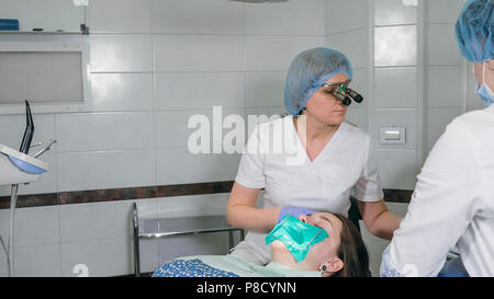 Frau beim Zahnarzt Klinik erhält der zahnmedizinischen Behandlung ein Loch in einen Zahn zu füllen. Zahnersatz und Verbundmaterial Polymerisation mit UV-Licht und Laser. Stockfoto