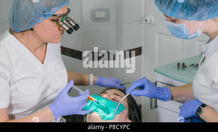 Frau beim Zahnarzt Klinik erhält der zahnmedizinischen Behandlung ein Loch in einen Zahn zu füllen. Zahnersatz und Verbundmaterial Polymerisation mit UV-Licht und Laser. Stockfoto