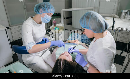 Frau beim Zahnarzt Klinik erhält der zahnmedizinischen Behandlung ein Loch in einen Zahn zu füllen. Zahnersatz und Verbundmaterial Polymerisation mit UV-Licht und Laser. Stockfoto