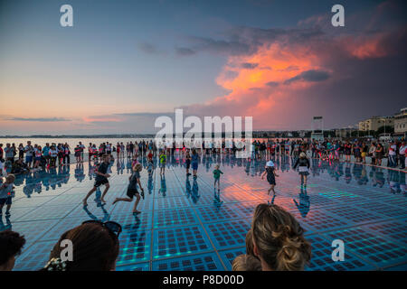 Kinder spielen auf dem Denkmal Grüße an die Sonne in Zadar bei Sonnenuntergang Stockfoto