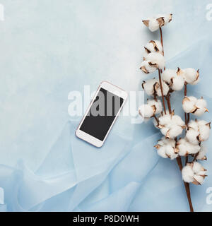 Flach Konzept der weiblichen Hellblauer Hintergrund mit Handy, Seide und Zweig der künstlichen Baumwolle Blume. Ansicht von oben, Quadrat Erntegut mit Kopie Raum Stockfoto