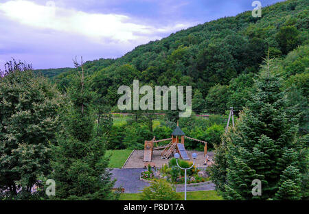 Holz- Spielplatz auf dem Platz in der Nähe des Blumenbeet vor dem Hintergrund der Berge. Für ihr Design Stockfoto