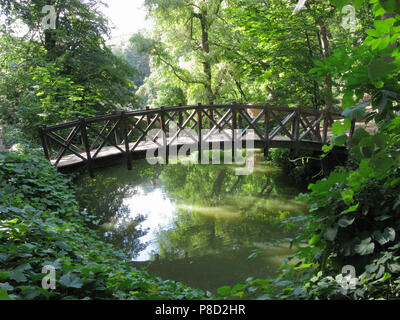 Hölzerne Brücke mit Geländer oberhalb des Flusses im Park unter den Bäumen. Uman Ukraine. Für ihr Design Stockfoto