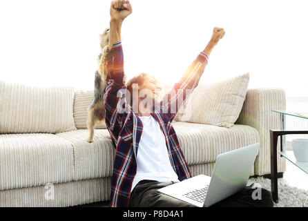 Happy Guy frohlockt mit seinem Hund sitzt in der Nähe der Couch im Wohnzimmer. Stockfoto