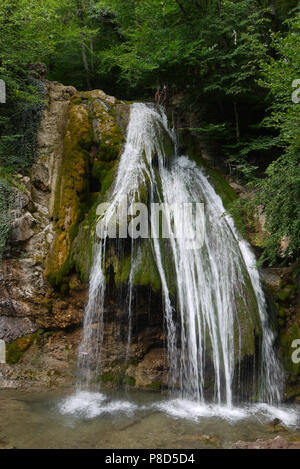 Ein kleiner Wasserfall. Weiß von Schaum Wasser fließt unten das grüne Moos Steine. Für ihr Design Stockfoto