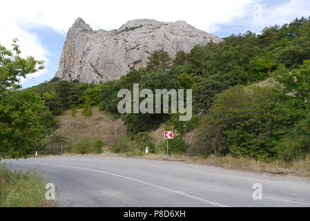 Eine steile Straße biegen Sie auf dem Hintergrund der grüne Vegetation und einem hohen Rocky Mountain. Für ihr Design Stockfoto