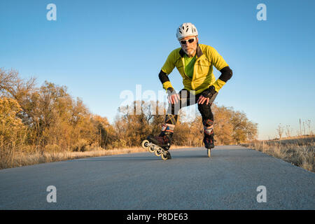 Senior sportlich männlich ist Inline-Skaten auf dem Poudre RIver Trail in Colorado, Spätherbst Landschaft Stockfoto