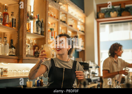Lächelnden jungen weiblichen Barkeeper Cocktails in einer Bar Stockfoto