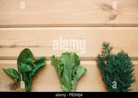 Spinat, grüner Salat und Dill auf einer hölzernen Oberfläche. Mischung der Grüns. Gesunde Lebensmittel. Im Obergeschoss ist ein Platz für Text. Stockfoto