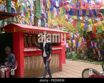 Ein Besucher an einer Reihe von gebetsmühlen an Mahakal Tempel in Darjeeling, West Bengal, 14. Juni 2018. Stockfoto