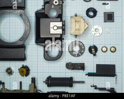 Teile sind vollständig demontiert alten retro Film SLR Kamera auf Millimeterpapier, close-up Stockfoto
