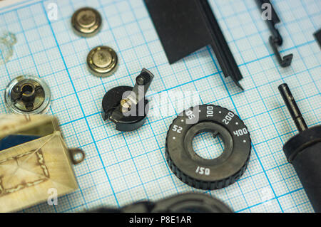 Teile sind vollständig demontiert alten retro Film SLR Kamera auf Millimeterpapier, close-up Stockfoto