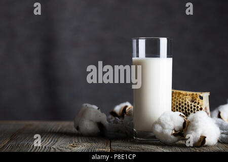 Glas butter Milch und Baumwolle Samenkapseln. Wabe im Hintergrund. Nahaufnahme Stockfoto