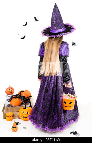 Mädchen in eine Hexe, Kleid mit Halloween Zubehör und vollen Eimer Süßigkeiten auf isolierten Hintergrund Stockfoto