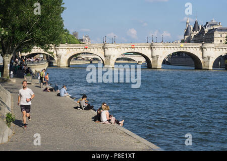 Menschen entspannend auf dem rechten Ufer der Seine River mit Blick auf die Brücke Pont Neuf in Paris, Frankreich. Stockfoto